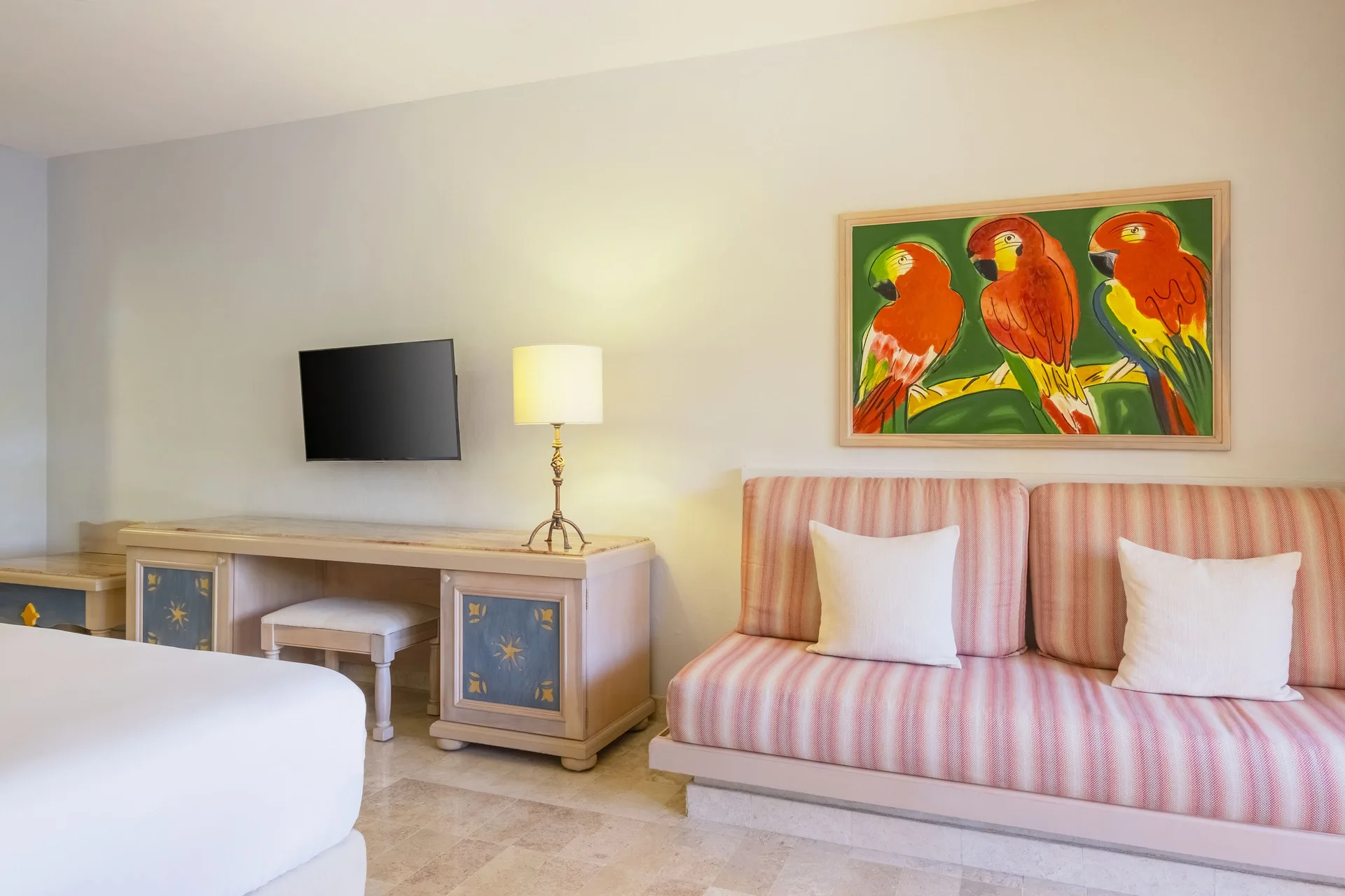 Premium Room sofa, desk, TV, and parrot artwork at Iberostar Waves Paraíso del Mar.