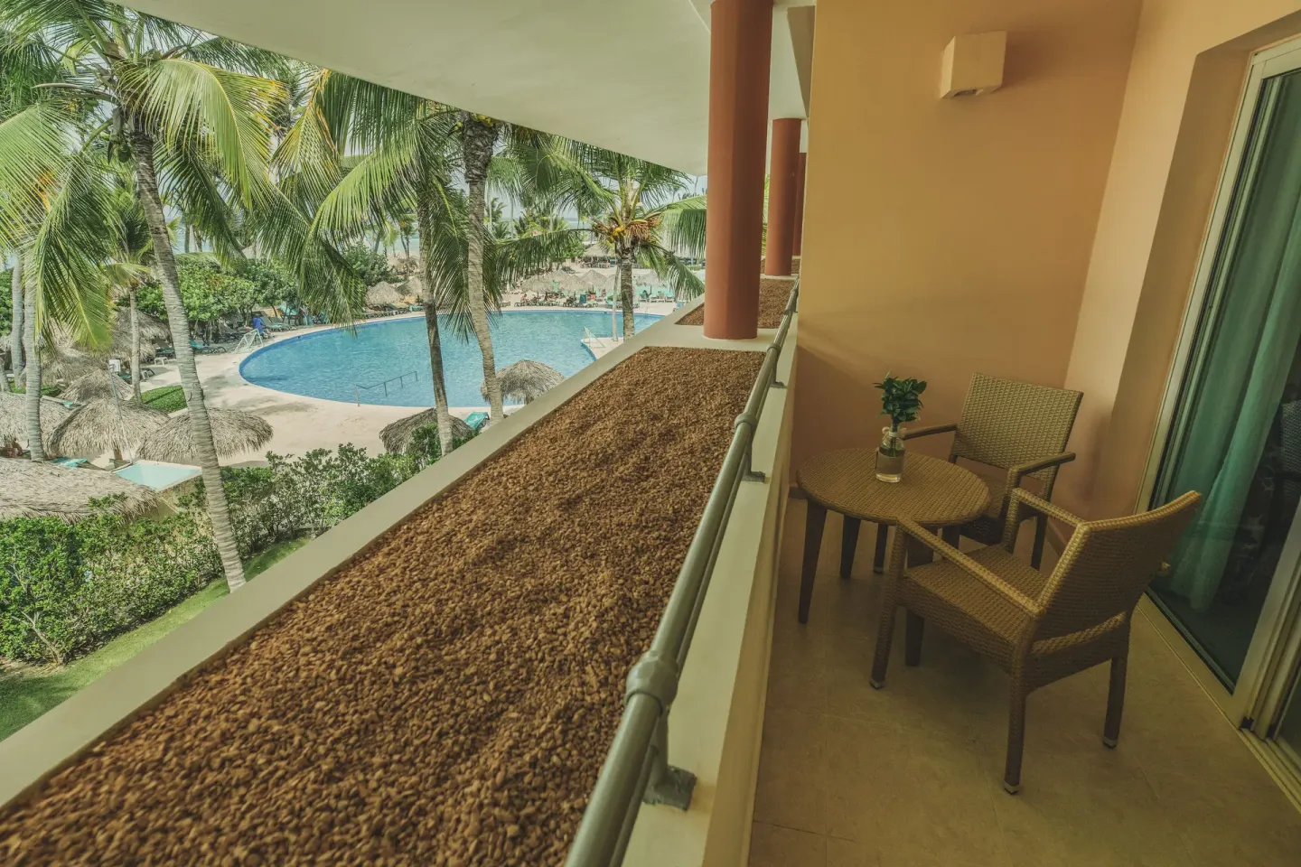 Balcony with wicker chairs overlooking the pool at Iberostar Waves Punta Cana.
