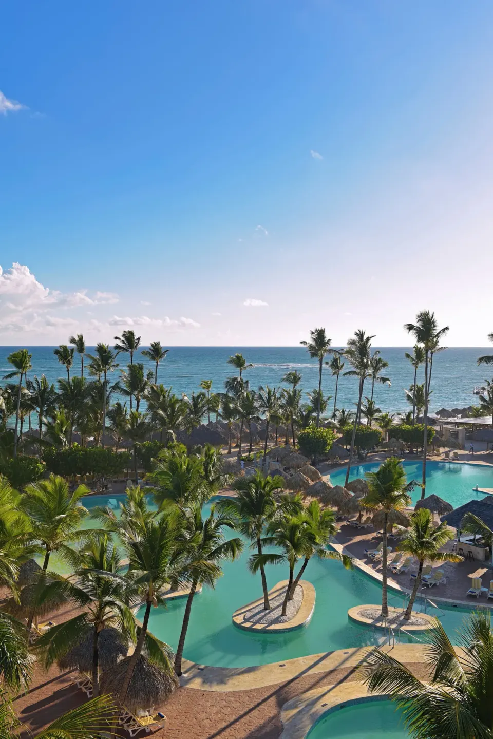 Elevated view of pools, palms, and ocean beyond at Iberostar Waves Punta Cana.