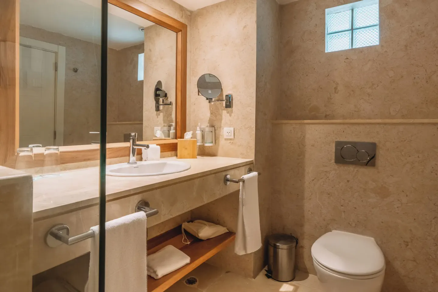 Bathroom vanity and toilet with stone-look walls at Iberostar Waves Punta Cana.