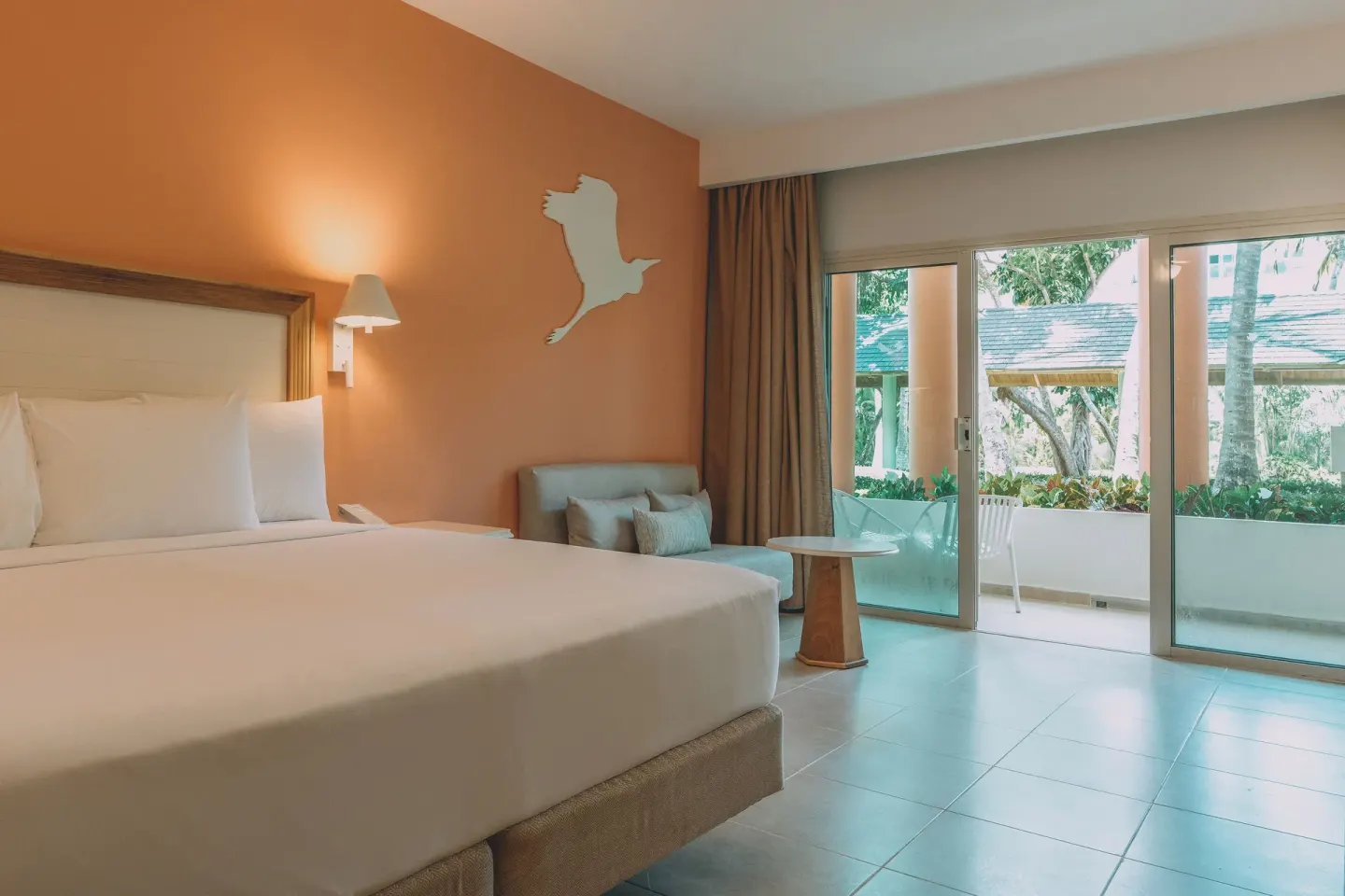 King bed room with orange accent wall and balcony at Iberostar Waves Punta Cana.