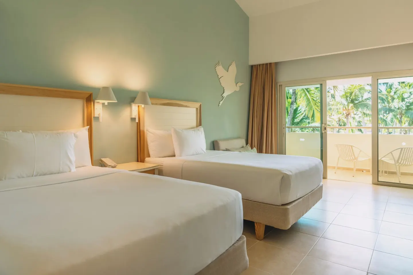 Two-bed guest room with balcony doors at Iberostar Waves Punta Cana.
