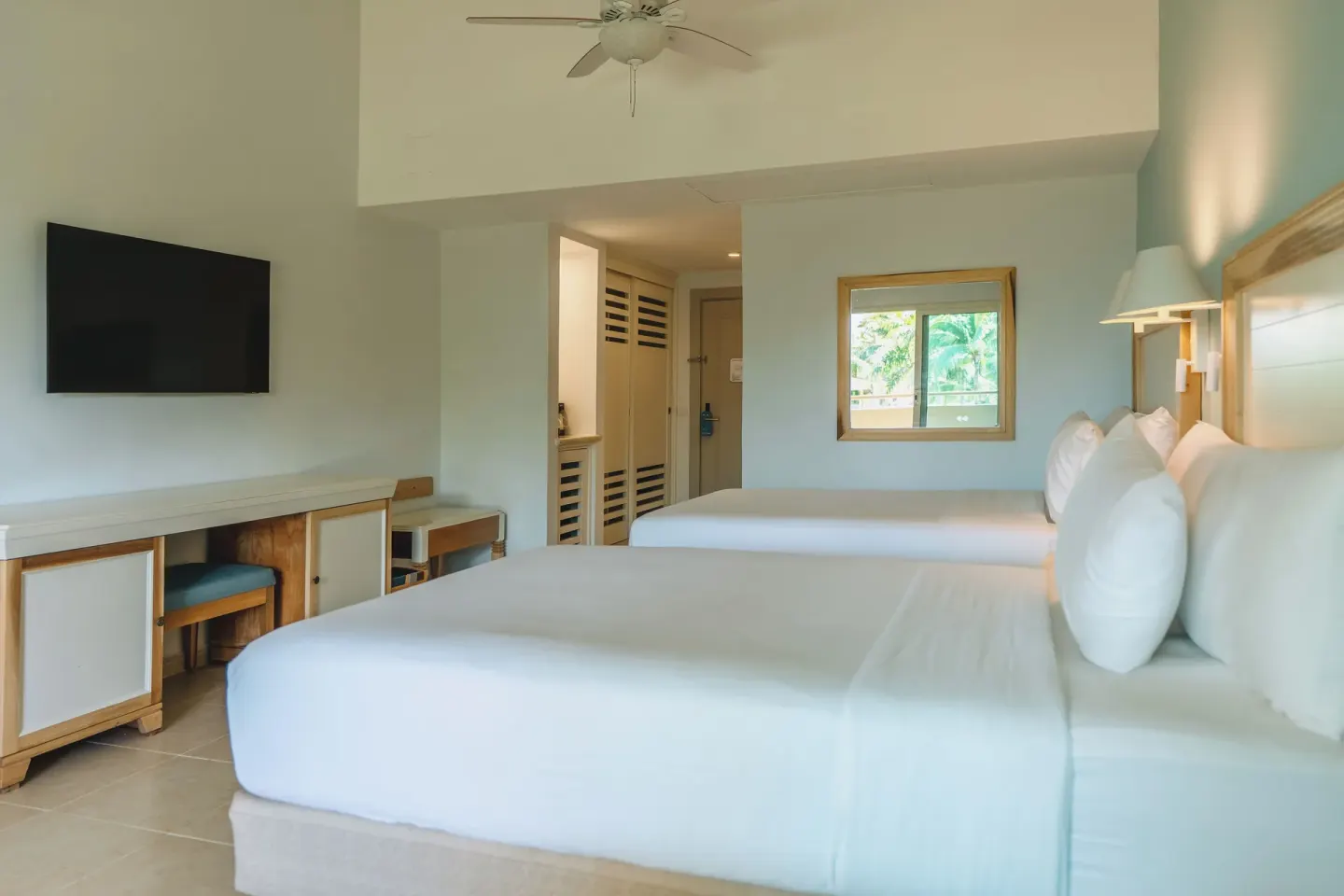 Two-bed guest room with TV and entry area at Iberostar Waves Punta Cana.