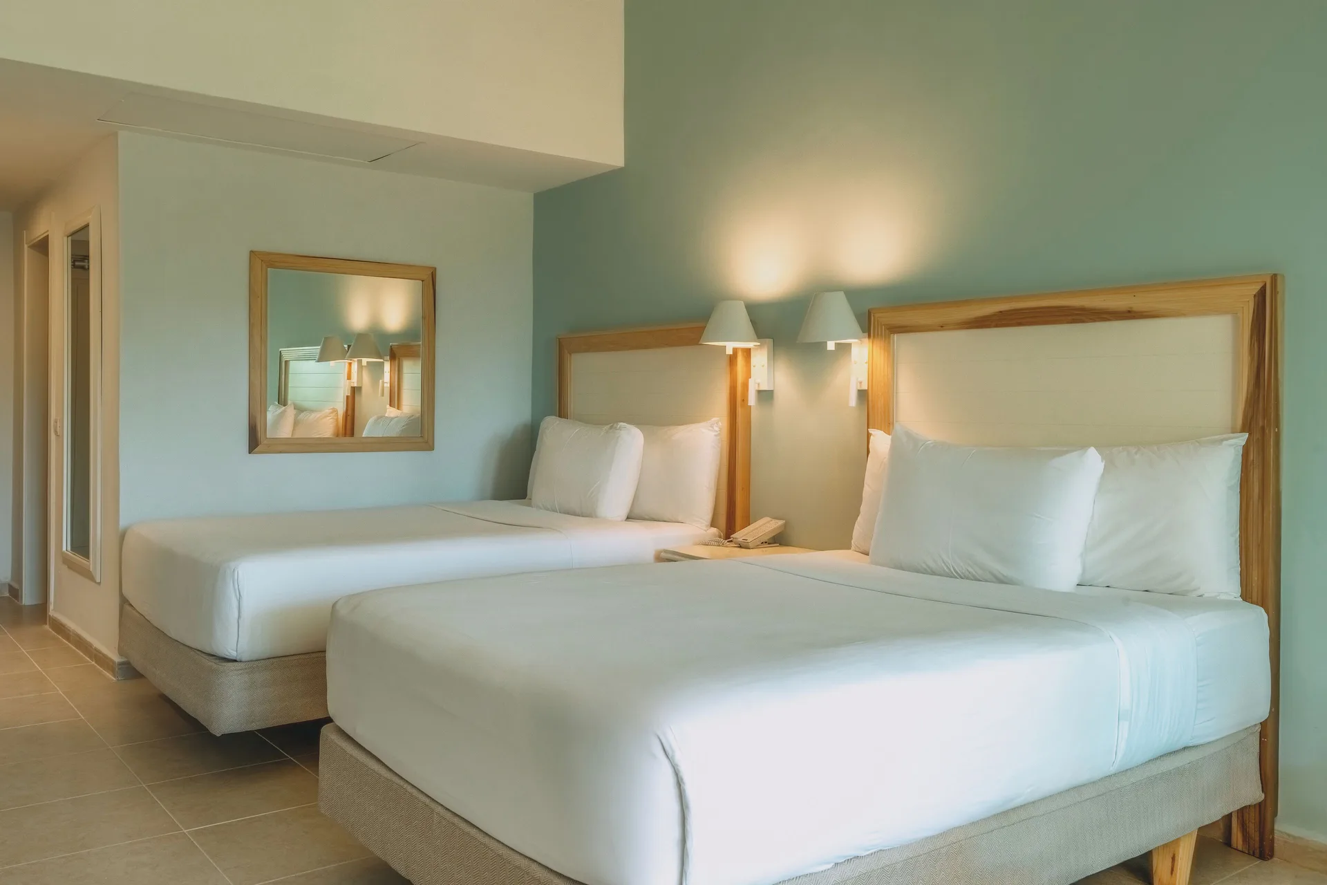 Two double beds with pale blue wall and wood headboards at Iberostar Waves Punta Cana.