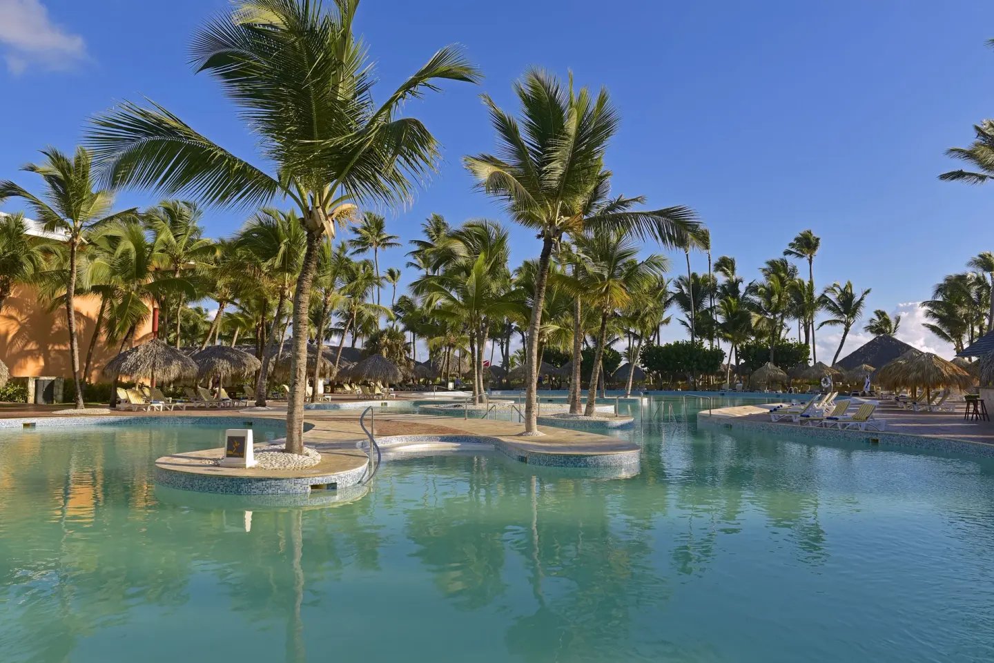 Lagoon-style pool with palm islands and loungers at Iberostar Waves Punta Cana.