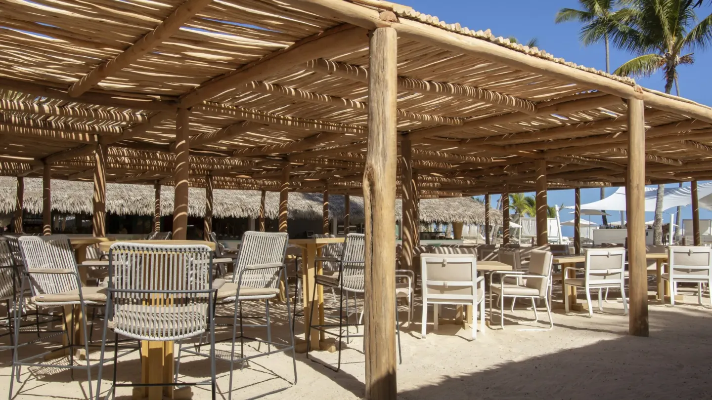 Shaded beachside seating under a wooden pergola at Iberostar Waves Punta Cana.