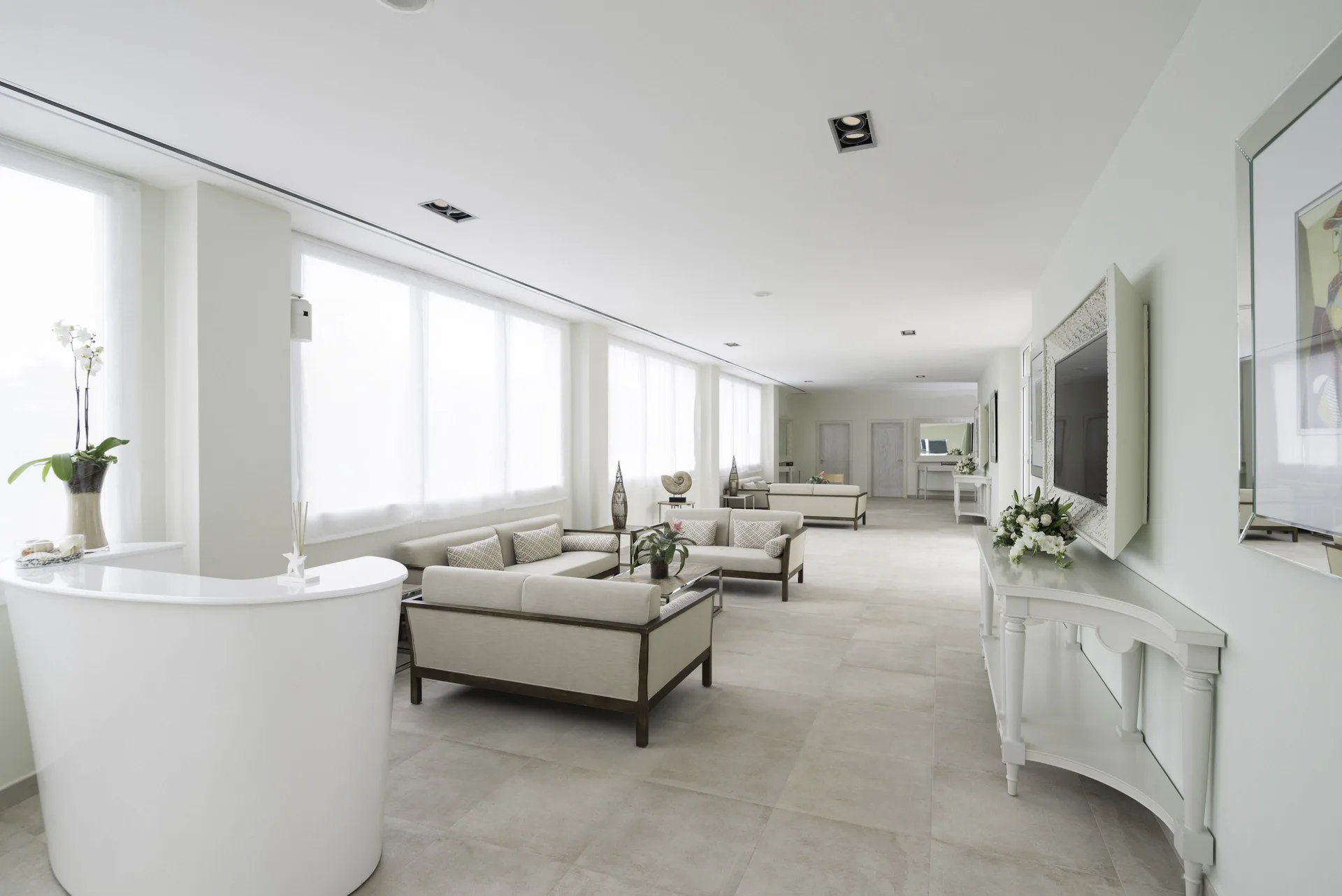 Bright white lobby lounge with sofas and a curved reception desk at Iberostar Waves Punta Cana.