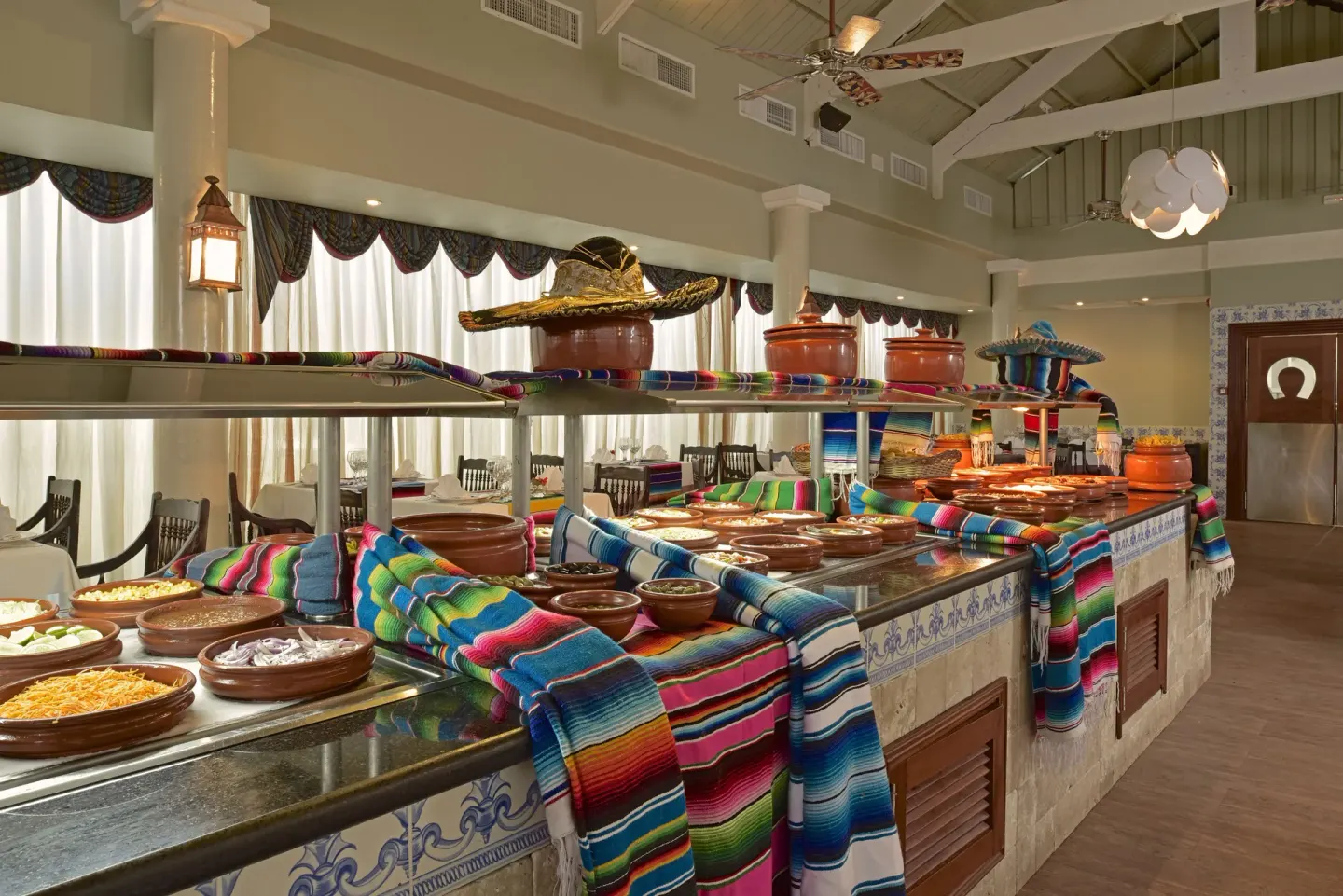 Buffet counter with clay serving dishes and colorful textiles at Iberostar Waves Punta Cana.