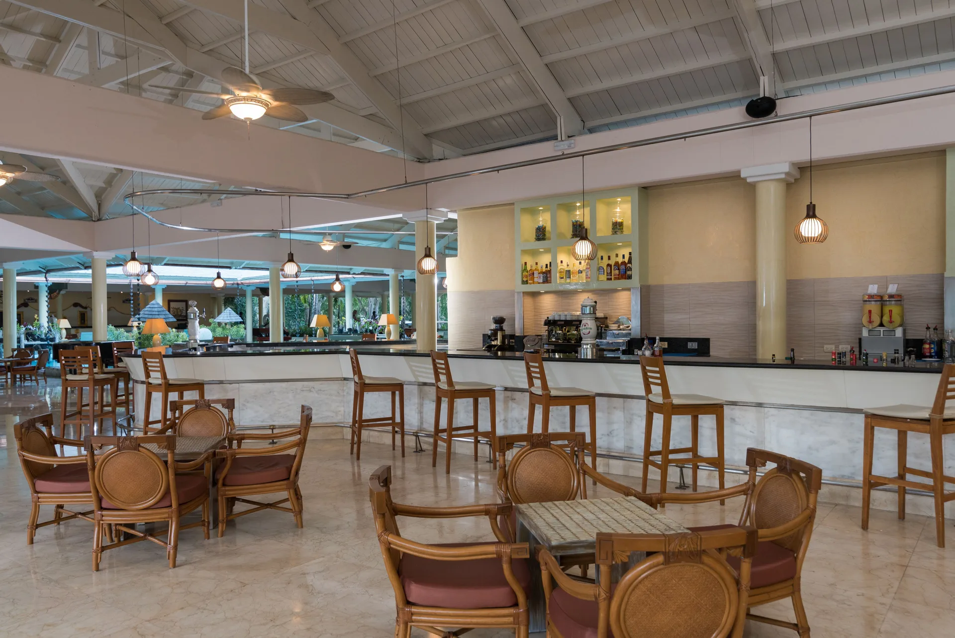 Lobby bar with wooden chairs, stools, and lit bottle shelves at Iberostar Waves Punta Cana.