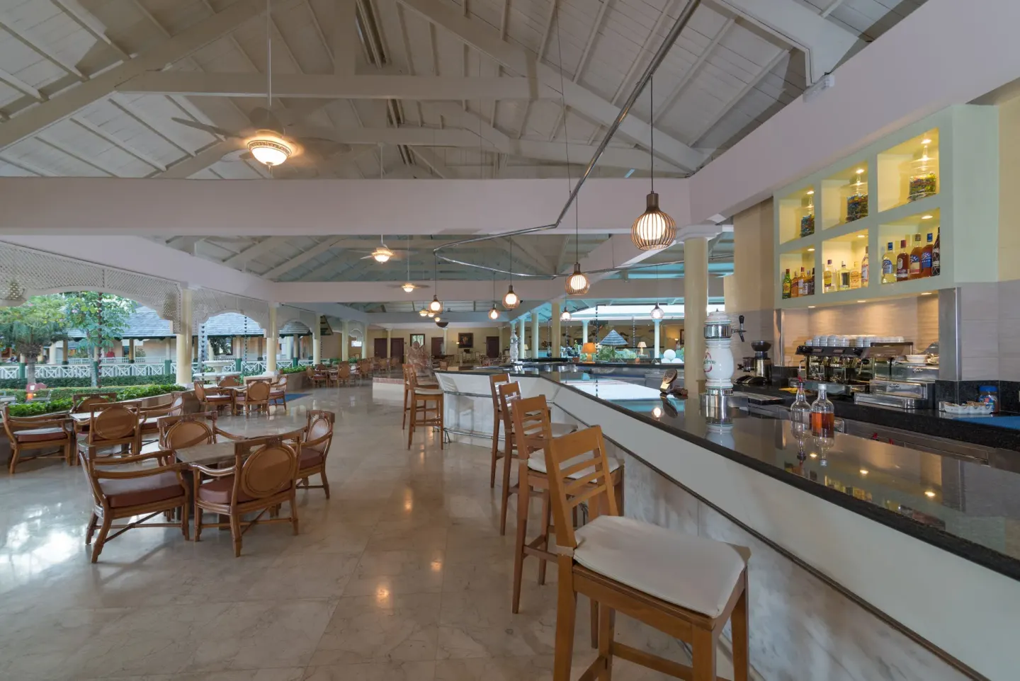 Open-air bar with stools, lounge tables, and bottle shelves at Iberostar Waves Punta Cana.