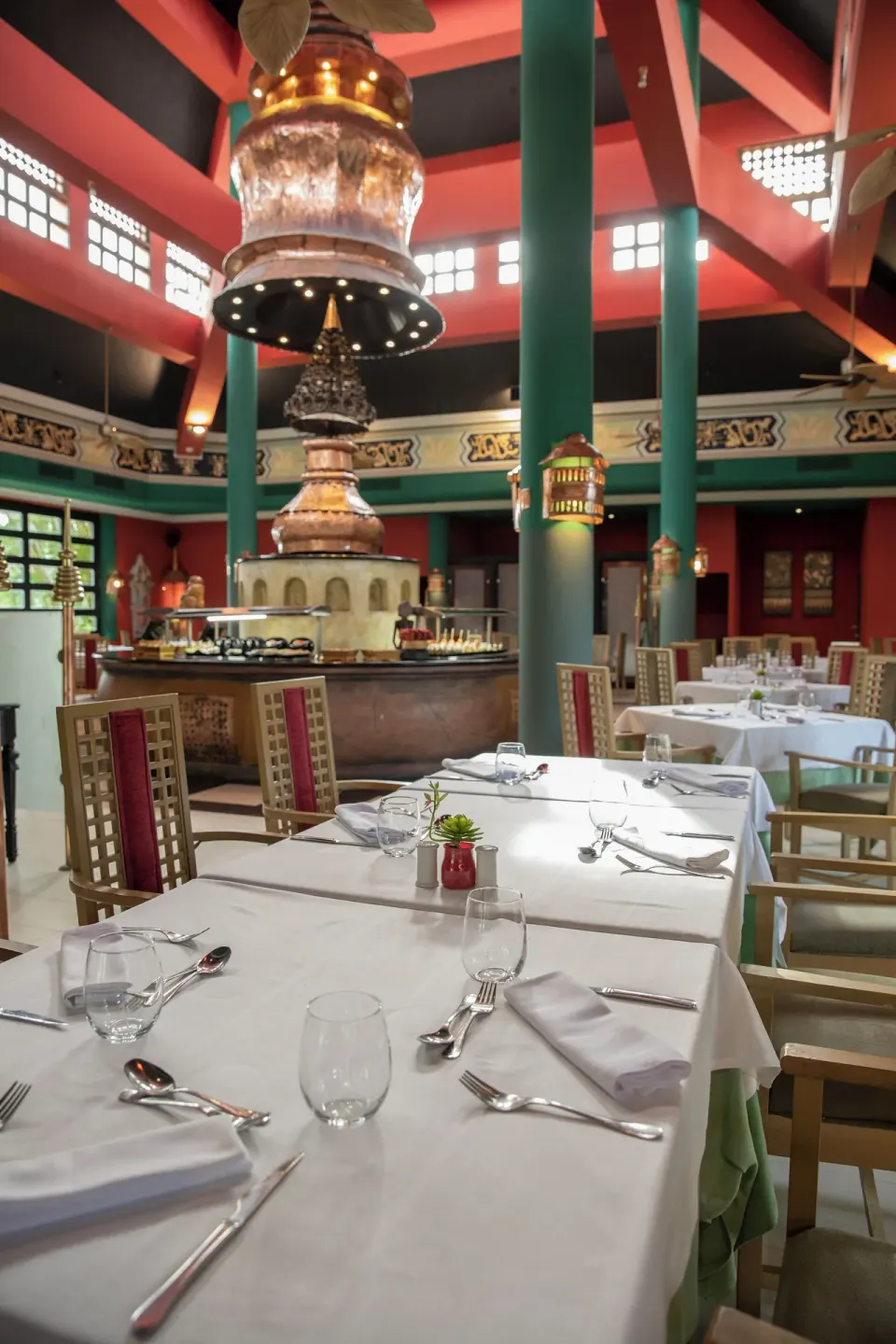 Restaurant tables set with white linens beneath ornate décor at Iberostar Waves Punta Cana.