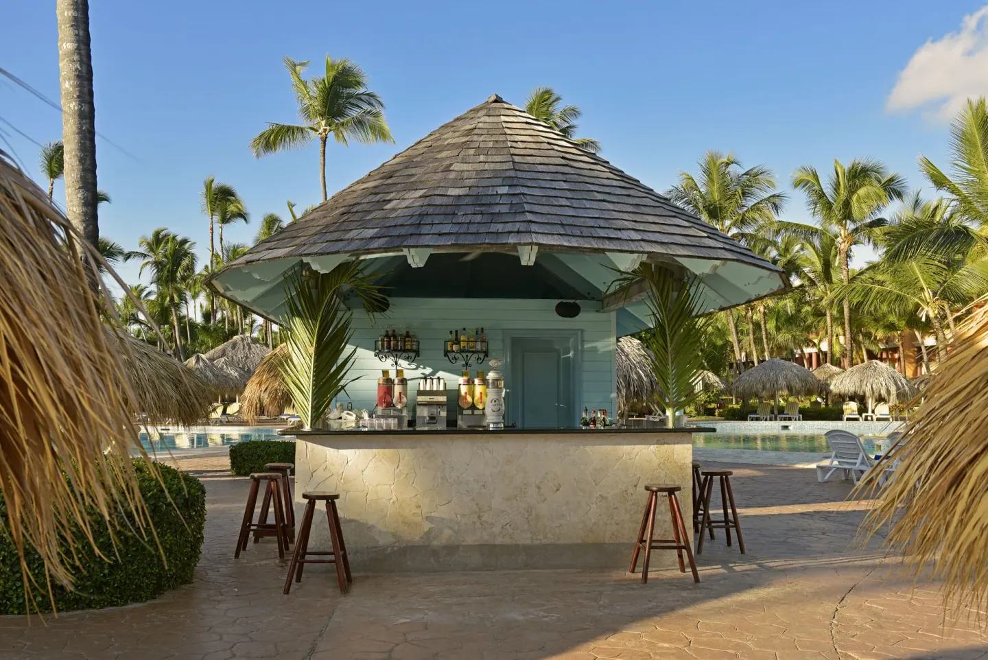 Poolside bar hut with stools and palm trees at Iberostar Waves Punta Cana.