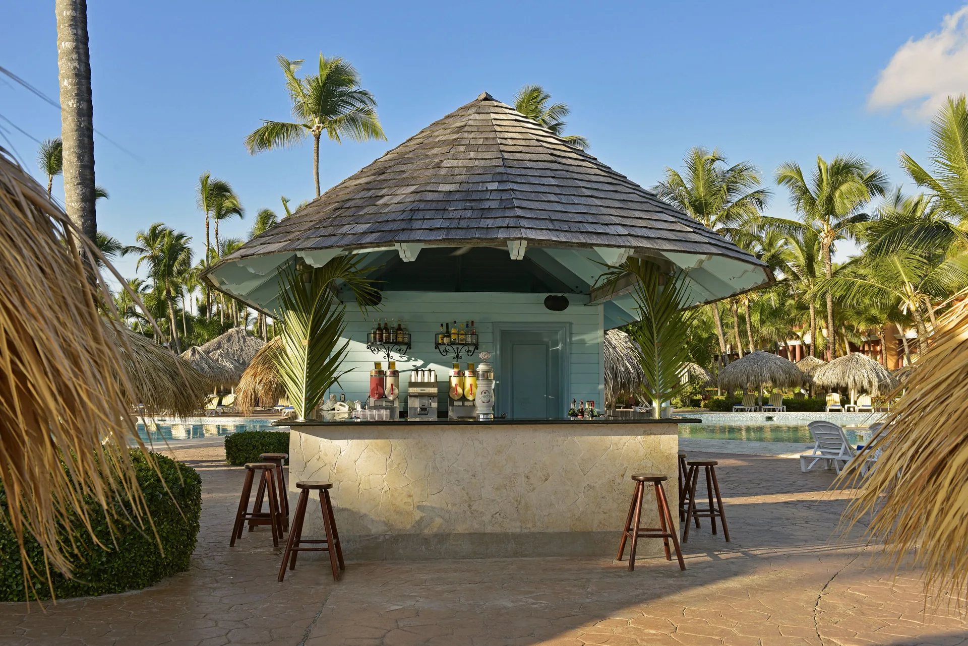 Poolside bar hut with stools and palm trees at Iberostar Waves Punta Cana.