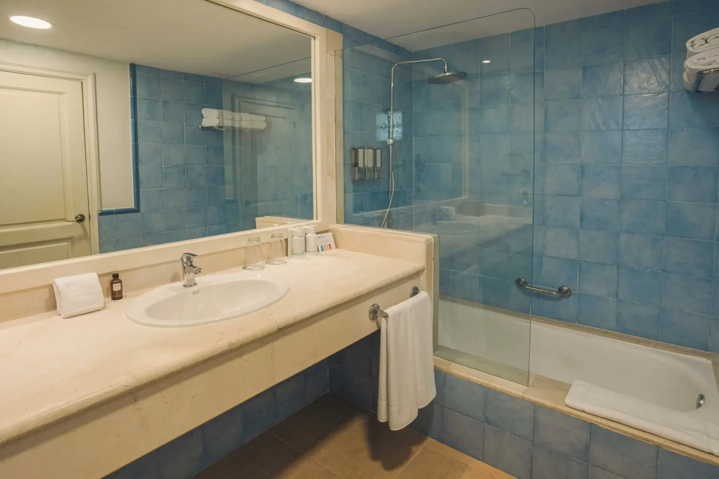 Junior Suite bathroom with sink and blue-tiled shower at Iberostar Waves Punta Cana.
