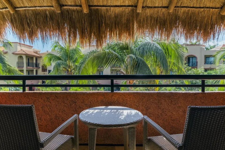 Shaded balcony table and chairs overlooking palm trees and resort buildings at Iberostar Waves Tucán