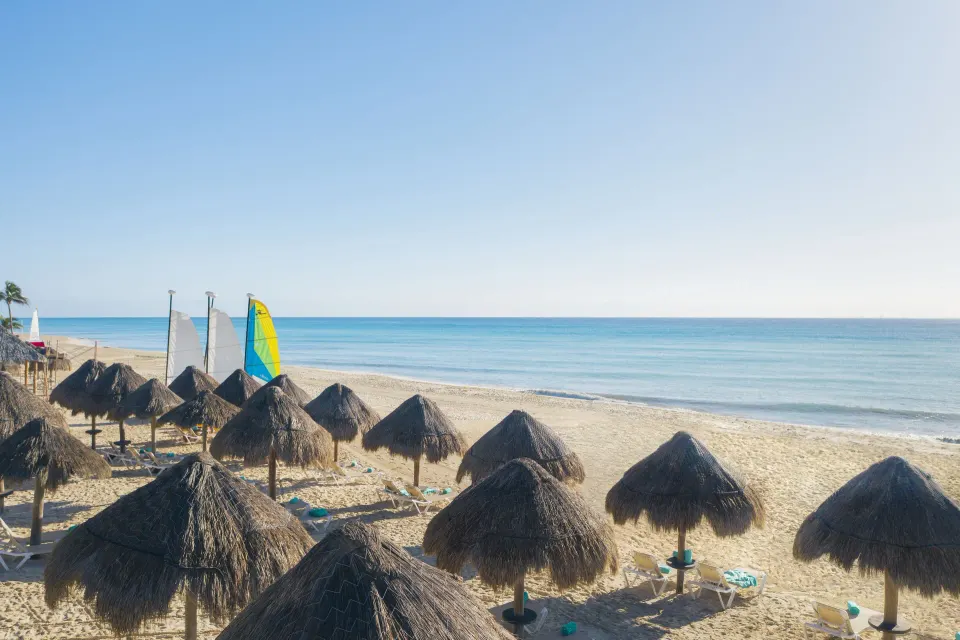 Sandy beach with palapa umbrellas and calm Caribbean sea at Iberostar Waves Tucán