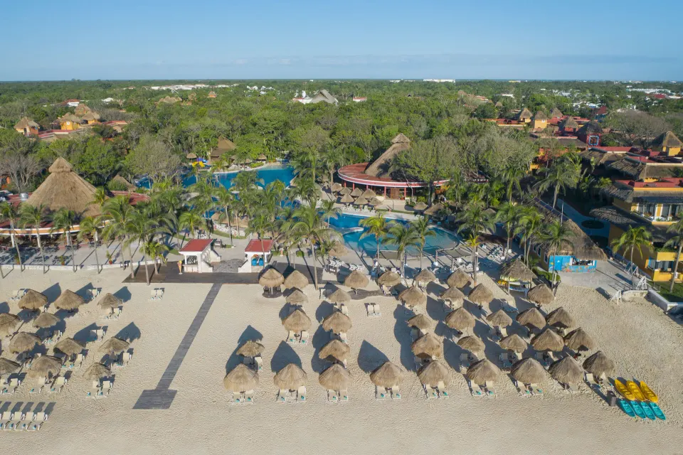 Aerial view of beach with palapa umbrellas and resort pools at Iberostar Waves Tucán