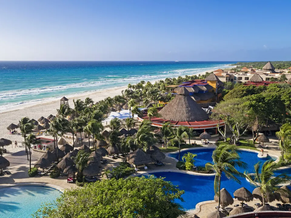 Wide coastal view of the resort's pools, palapas and long sandy beach at Iberostar Waves Tucán.