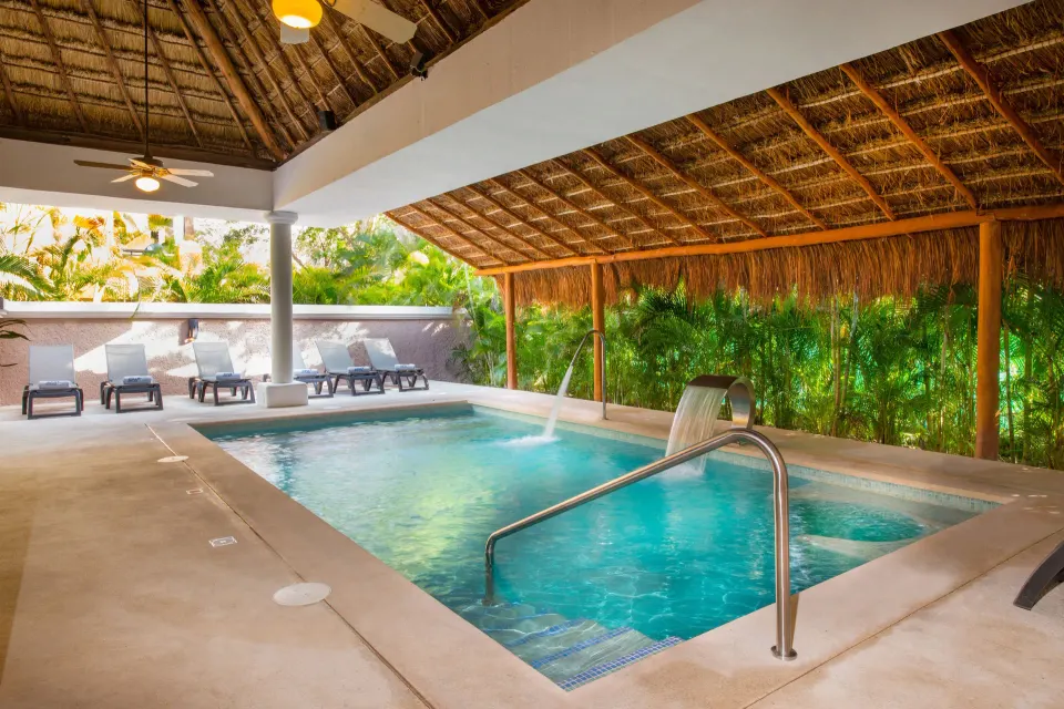Covered hydrotherapy pool and loungers under a palapa at Iberostar Waves Tucán