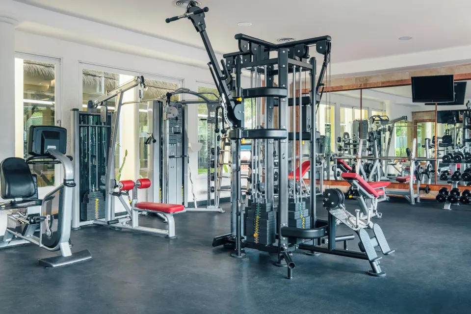 Hotel fitness center with weight machines, benches and mirrored wall at Iberostar Waves Tucán