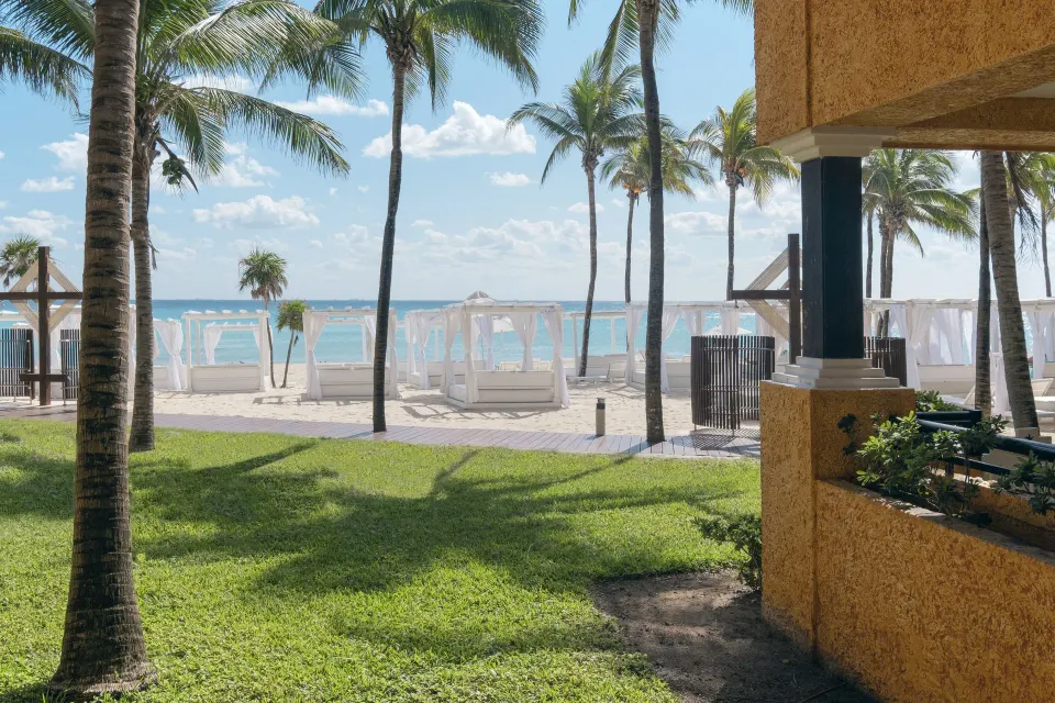 View of beach cabanas and palm trees from resort grounds at Iberostar Waves Tucán
