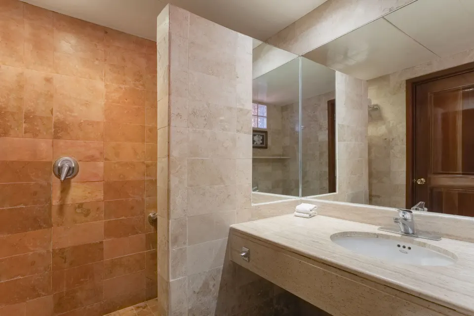 Open shower and marble vanity with mirror in guest bathroom at Iberostar Waves Tucán