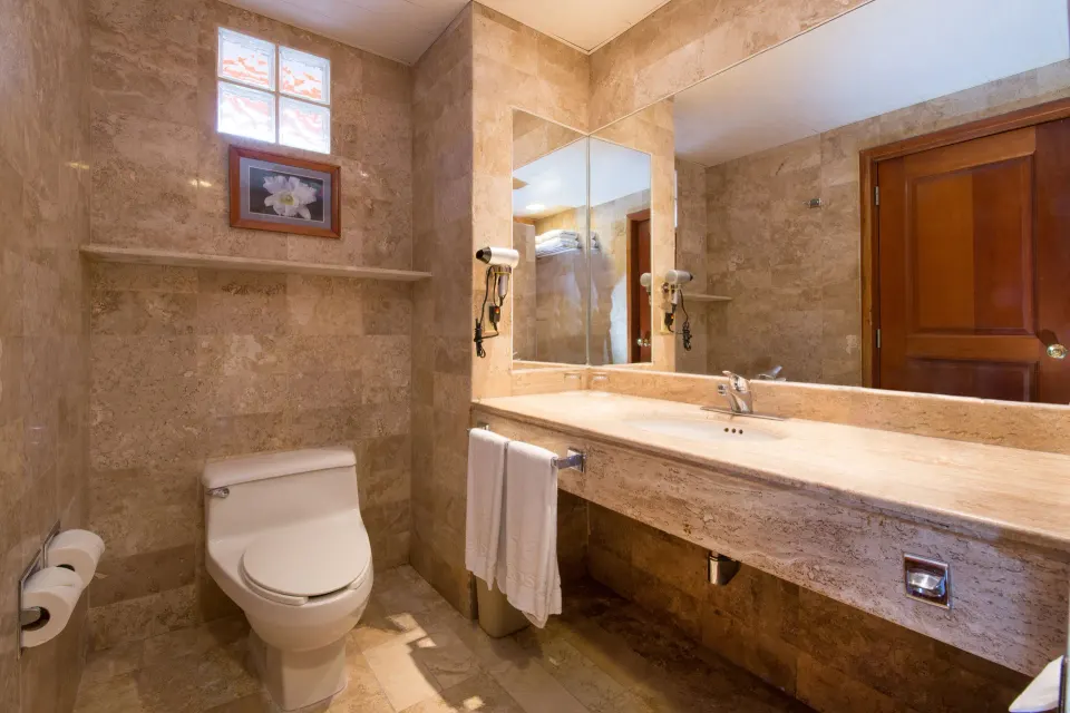 Toilet and marble vanity with mirror in guest bathroom at Iberostar Waves Tucán