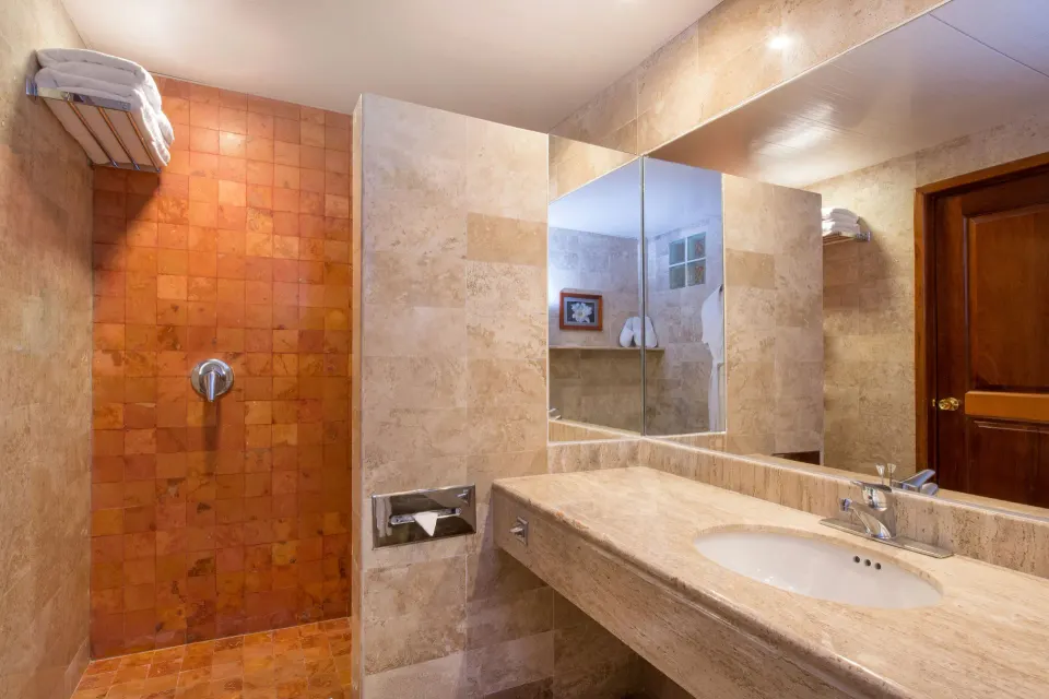 Marble bathroom vanity and open tiled shower in guest room at Iberostar Waves Tucán