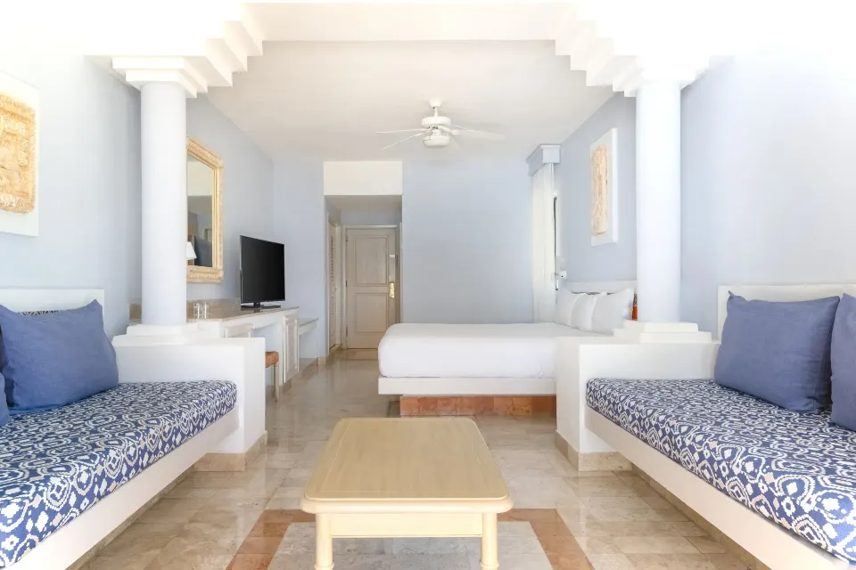 Bright suite interior with bed, twin lounges and TV at Iberostar Waves Tucán