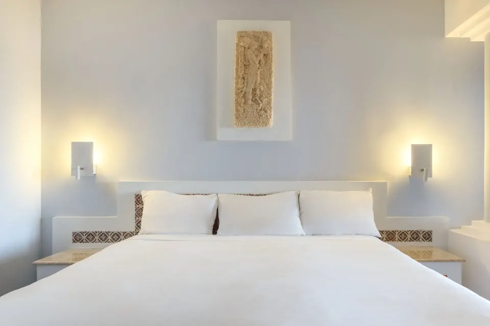 Close-up of king bed with white headboard and soft wall lighting at Iberostar Waves Tucán