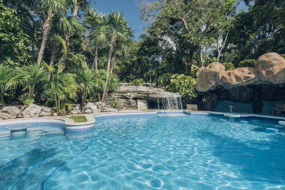 Curved resort pool with waterfall and jungle plantings at Iberostar Waves Tucán