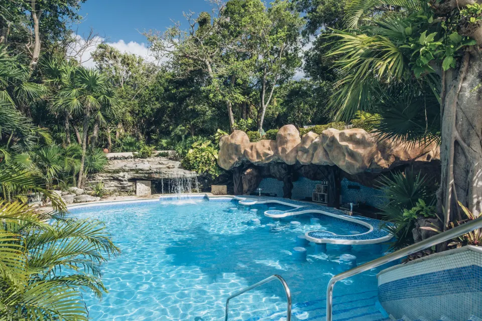 Smaller tropical pool with rock grotto, waterfall and cave seating at Iberostar Waves Tucán