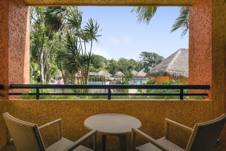 Guest room with king bed, TV and balcony overlooking trees at Iberostar Waves Tucán