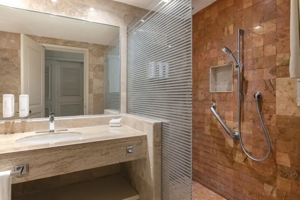 Marble sink and walk-in shower in a guest bathroom at Iberostar Waves Tucán