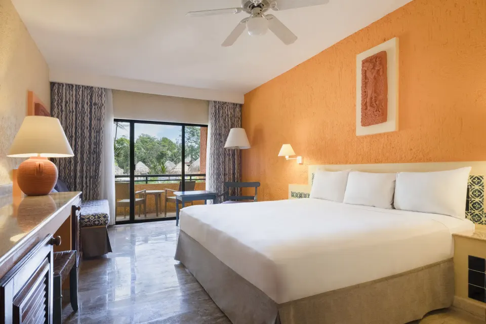 Guest room with king bed, ceiling fan and balcony overlooking trees at Iberostar Waves Tucán