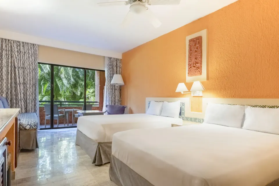 Spacious guest room with two beds and balcony overlooking tropical foliage at Iberostar Waves Tucán