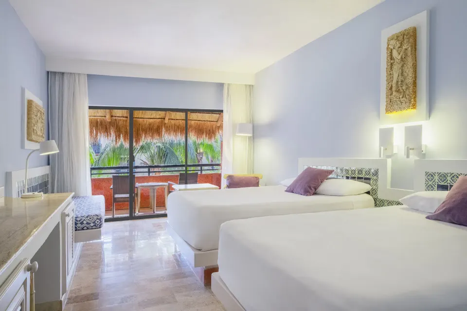 Guest room with two beds, purple throw pillows and balcony with palm-fringed view at Iberostar Waves Tucán