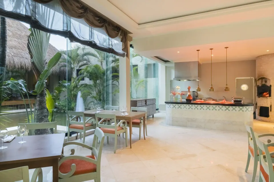 Bright indoor dining area with garden views and a service counter at Iberostar Waves Tucán