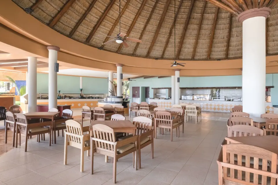 Open circular palapa dining area with rows of wooden tables at Iberostar Waves Tucán