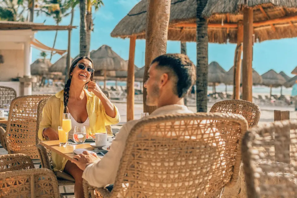 Couple dining at wicker table on the beach at Iberostar Waves Tucán