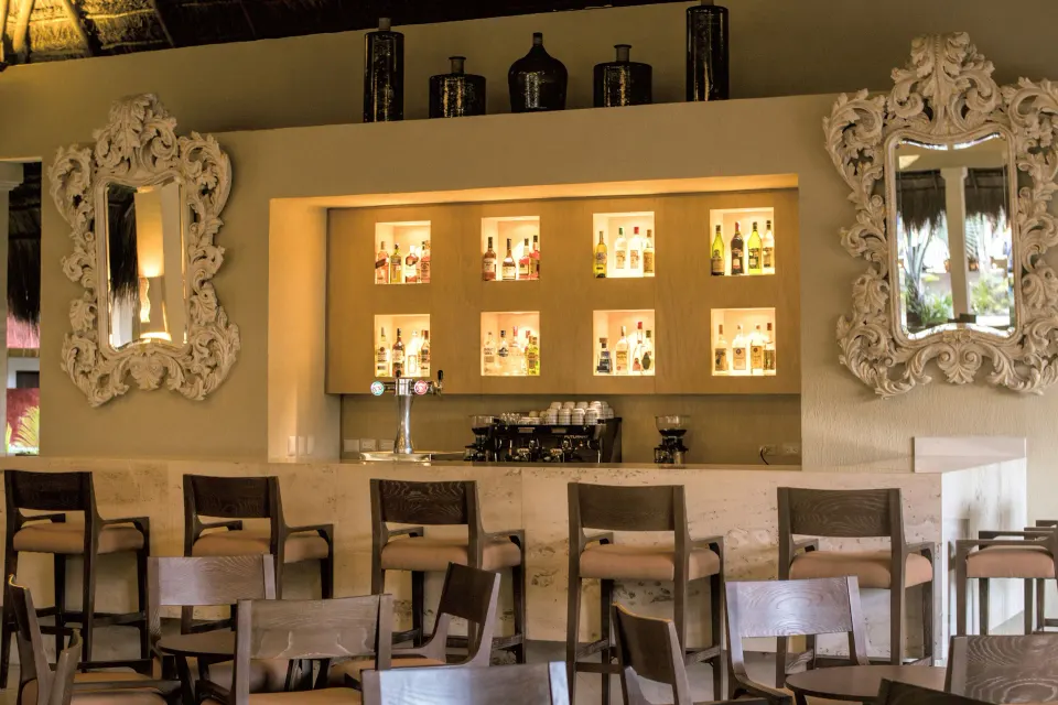 Indoor bar with backlit bottle displays and ornate mirrors at Iberostar Waves Tucán