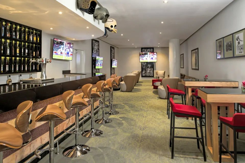 Contemporary bar with high stools, TVs and lounge tables at Iberostar Waves Tucán