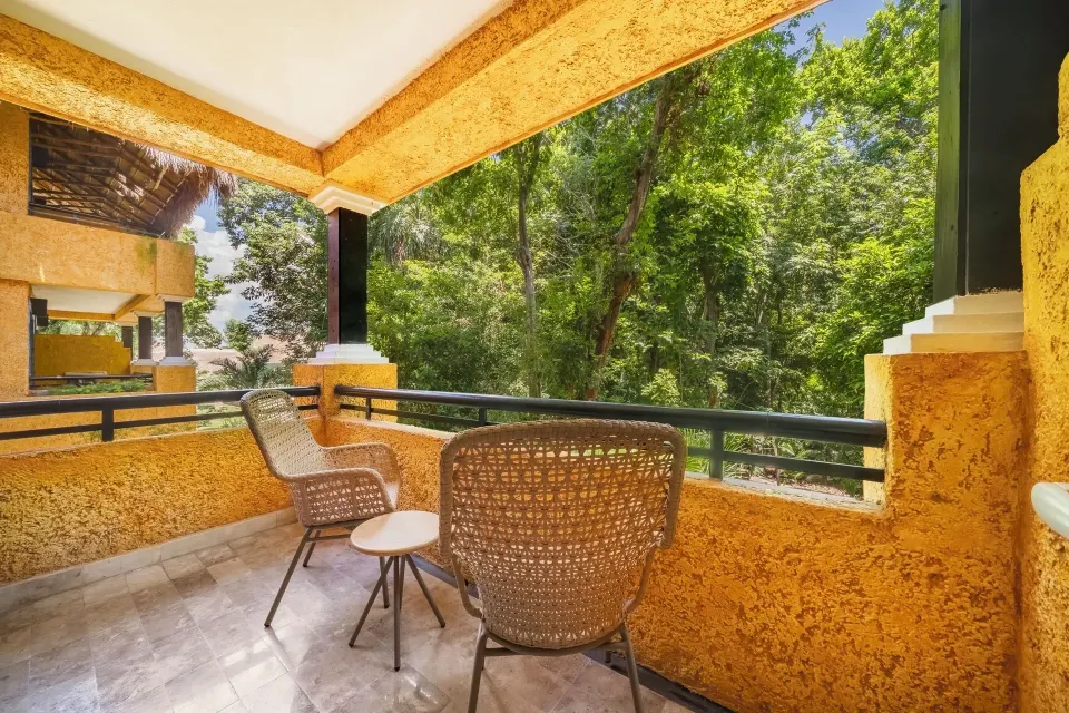 Balcony with two wicker chairs overlooking tropical trees at Iberostar Waves Tucán