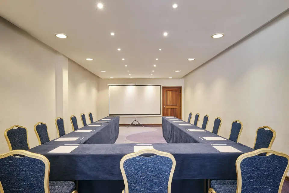 U-shaped meeting room setup with tables, chairs and projector screen at Iberostar Waves Tucán