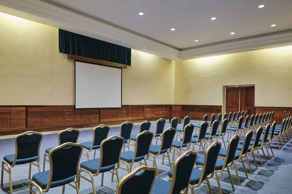 Large conference room set with rows of chairs and projection screen at Iberostar Waves Tucán