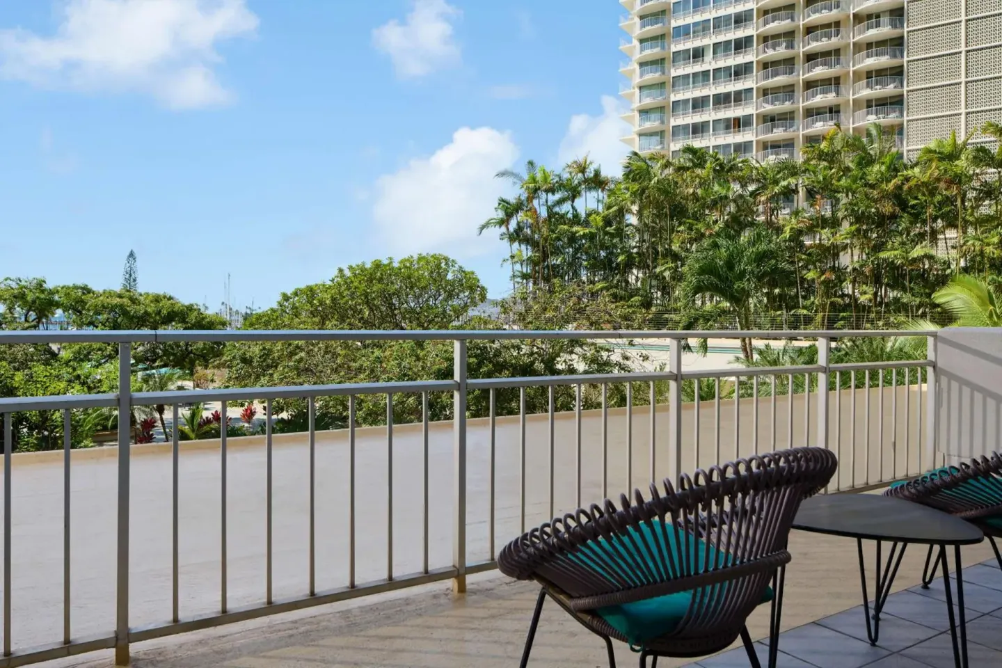 Balcony seating overlooks palms and a neighboring tower at Ilikai Hotel.