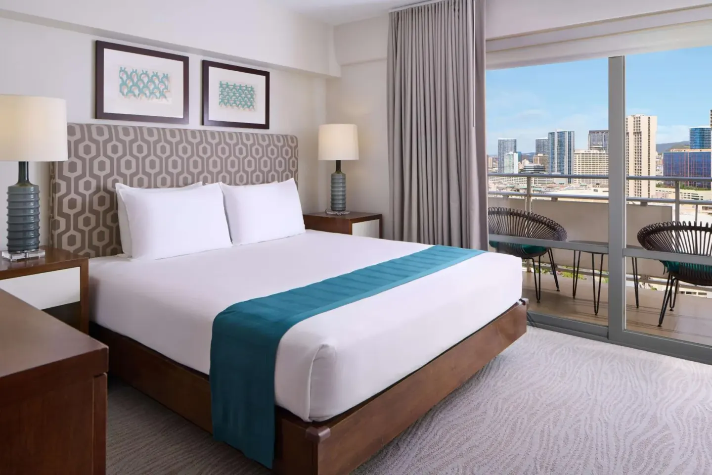 King bed guest room with balcony and city views at Ilikai Hotel.