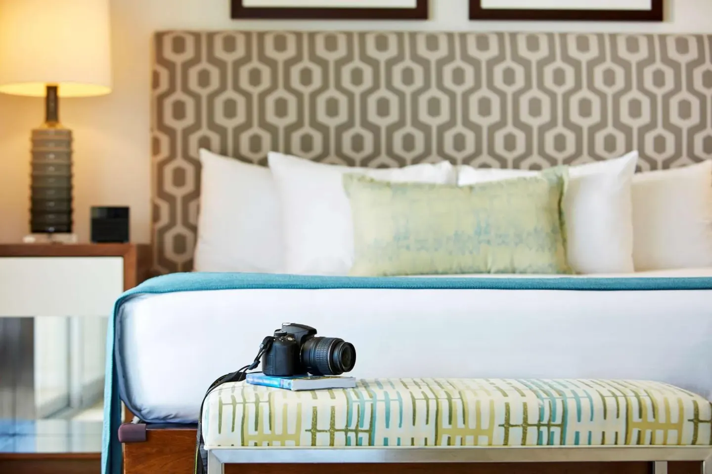 Close-up of a king bed and bench with camera at Ilikai Hotel.