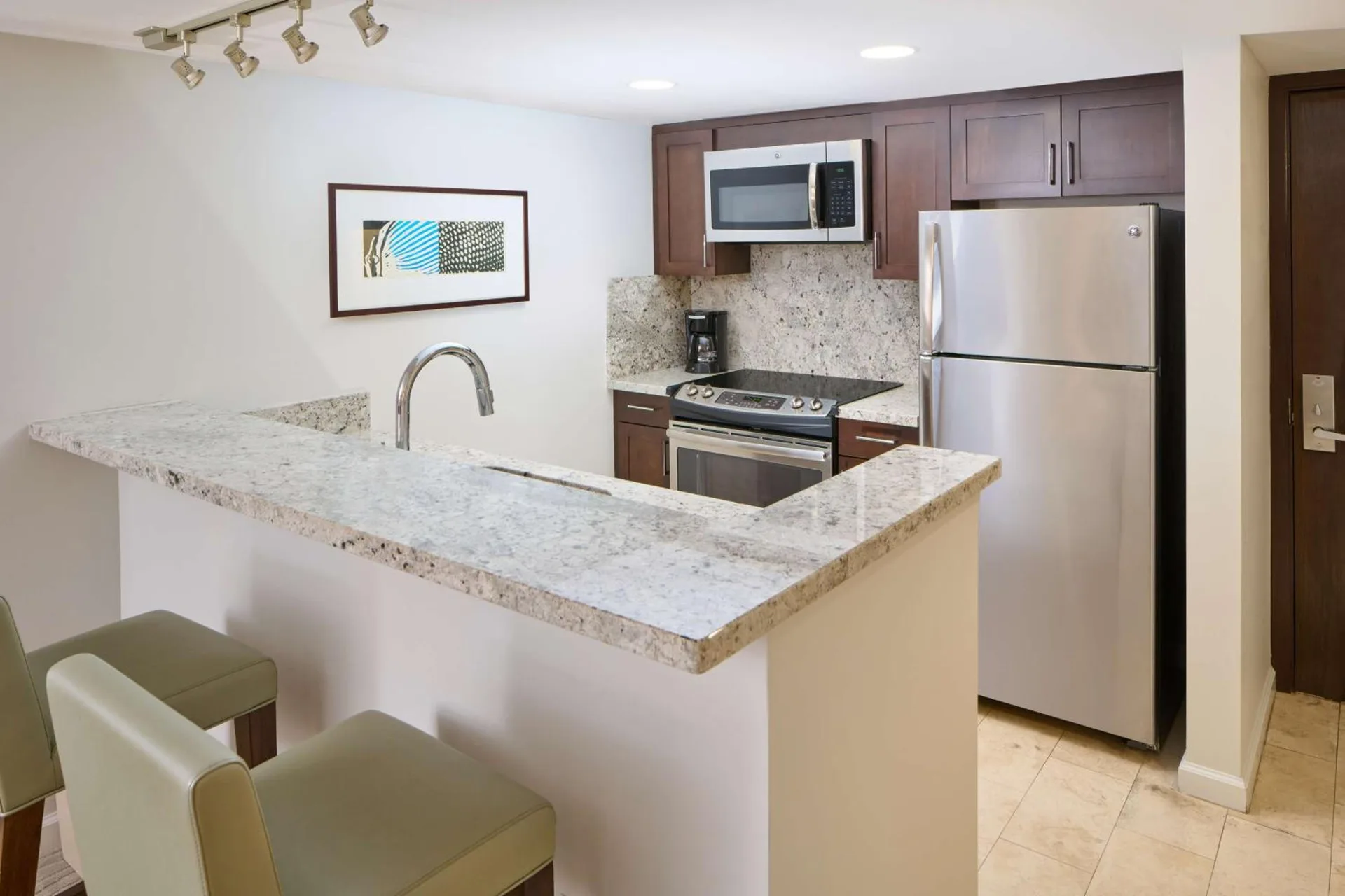 Guest room kitchen with granite counter, refrigerator, microwave, and stove at Ilikai Hotel.