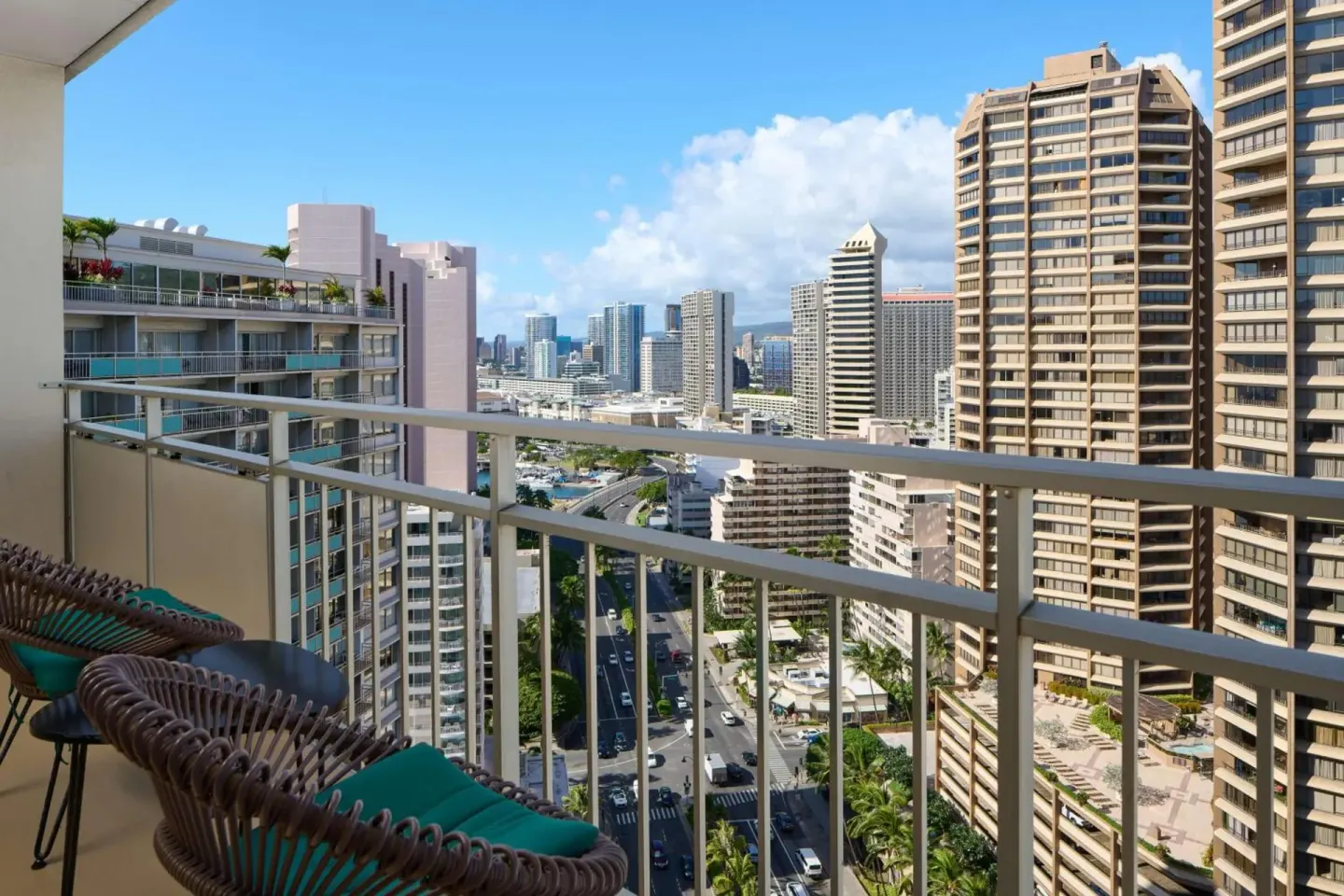 Balcony chairs overlook Honolulu streets and high-rise buildings at Ilikai Hotel.
